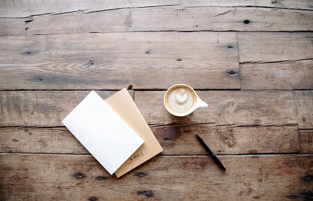 Carnet ouvert et tasse posés sur une table en bois